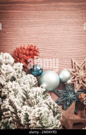 Vertikaler verschneiter Neujahrszweig mit Spielzeugbällen, Sternen und Hütchen. Dekoratives Weihnachtsmodell mit dekorativem Design und Kopierbereich Stockfoto