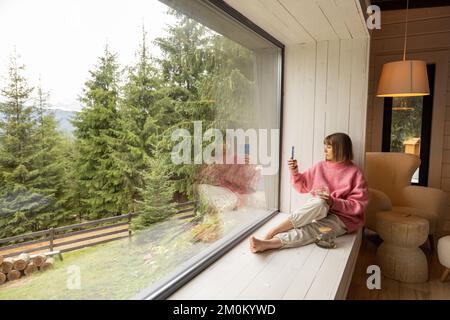 Frau ruht im Haus mit Panoramablick auf die Berge Stockfoto