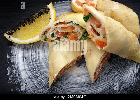 Pfannkuchen mit Lachs, Frischkäse und Kräutern auf schwarzem Hintergrund Stockfoto