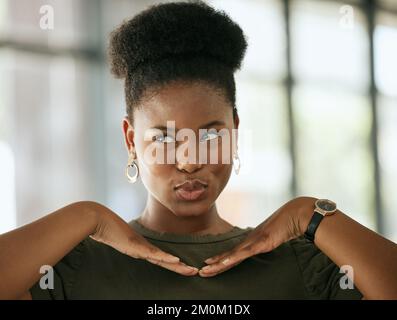 Glückliche afroamerikanische Geschäftsfrau posierte mit den Händen unter dem Gesicht, während sie schmollte und in einem Büro wegschaute. Verspielte Unternehmerin Stockfoto