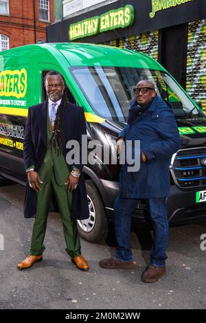 REDAKTIONELLE VERWENDUNG VON LEVI Roots (links) mit Händler Stafford Geohagen of Healthy Eaters bei einer Veranstaltung auf der Electric Lane, um Ford Pro die neue Partnerschaft mit Markthändlern in Brixton zu würdigen, die ihnen helfen soll, vor Ablauf der Frist 2035 auf vollelektrische Lieferwagen umzustellen. Bilddatum: Mittwoch, 7. Dezember 2022. Stockfoto