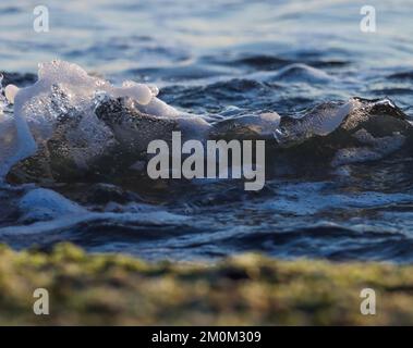 Blaue schäumende Meereswelle, die am Strand rollt. Meereswelle. Stockfoto