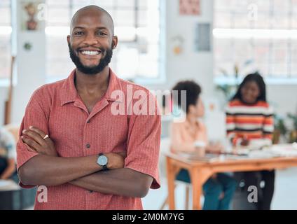 Junger, glücklicher afroamerikanischer Geschäftsmann, der mit gekreuzten Armen in einem Büro stand. Selbstbewusster männlicher Manager, der am Arbeitsplatz lächelt und steht Stockfoto