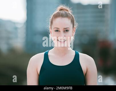 Porträt einer selbstbewussten jungen Kaukasierin, die draußen trainiert. Entschlossene Sportlerin, die glücklich und motiviert für das Training im wirkt Stockfoto