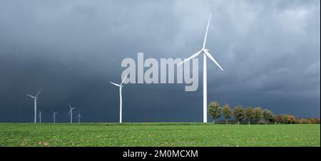 Dunkelgrauer Himmel und weiße Windturbinen in belgien Stockfoto
