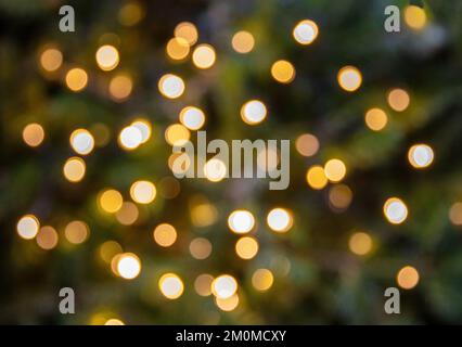 Bokeh leuchtet den Hintergrund goldfarben. Verschwommener Weihnachtsbaum und Dekorationseffekt aus nächster Nähe. Vorlage für Winterweihnachtskarten Stockfoto