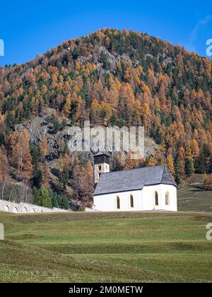 Malerischer Herbstblick auf die Kirche San Peter und den Friedhof in der Kleinstadt Samedan im Kanton Graubünden, Schweiz. Stockfoto