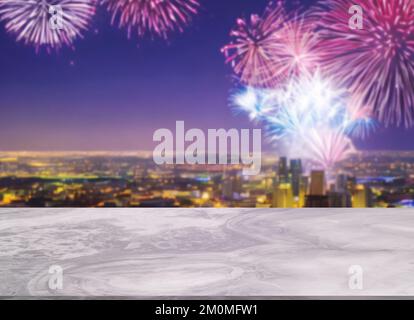 Wunderschöner weißer Marmortisch oder, kleine glänzende Oberfläche, Ausblick, Hintergrund der verschwommenen Stadtlandschaft und Himmel voller Feuerwerk bei Nacht. Leere Spa Stockfoto