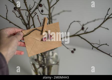 Frau Hand hält Brief für den Weihnachtsmann. Briefumschlag aus Kunsthandwerk. Weihnachtskonzept und Neujahrskonzept Stockfoto