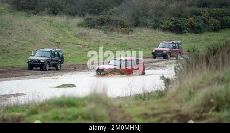 Drei Land Rover Discovery 4x4 Geländefahrzeuge, die durch tiefes Wasser und Schlamm auf offener Landschaft in Wiltshire UK gefahren werden Stockfoto