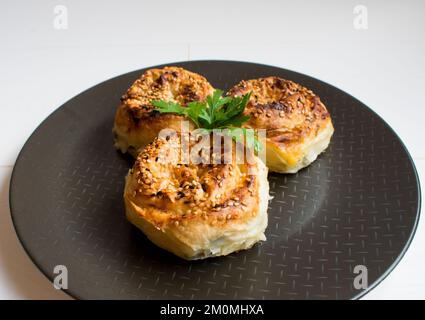 Traditionell köstliches türkisches Yufka gefüllt mit Käse (türkischer Name: Rosengebäck) rosenförmiges Gebäck auf einem schwarzen Teller. Stockfoto