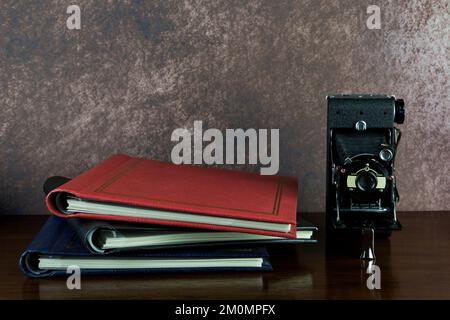 Alte Klappkamera und Fotoalben auf einer lackierten Holzoberfläche Stockfoto