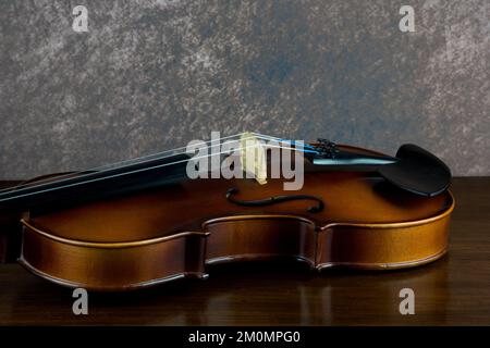 Ein Geigenmusikinstrument, das auf einem lackierten Holzregal liegt Stockfoto