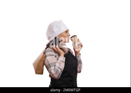 Charmante Barkeeperin, die während der Kaffeepause ein heißes Getränk trinkt, isoliert auf weißem Hintergrund. Essen und Trinken Stockfoto