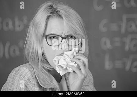 Die Lehrerin ist bereit, ihren Papierkram zu essen. Der Lehrer isst ein Stück Papier und nimmt Informationen auf. Wissensdurst. Eine Lehrerin isst ein zerknittertes Stück Papier Stockfoto