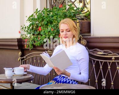 Eine Tasse guten Kaffees und ein angenehmes Buch sind die beste Kombination für ein perfektes Wochenende. Mädchen trinken jeden Morgen Kaffee am selben Ort, tägliches Ritual. Die Frau schon Stockfoto