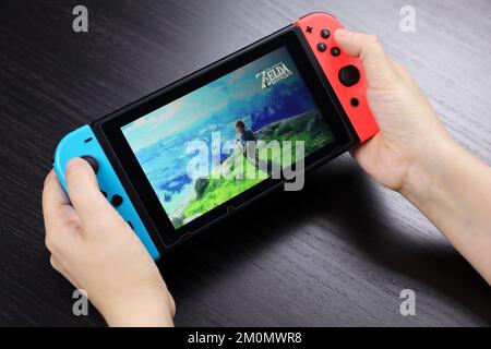 Mädchen spielt das Spiel „die Legende von Zelda“ auf der Nintendo Switch-Konsole im Handheld-Modus, selektive Fokussierung auf einen Bildschirm Stockfoto