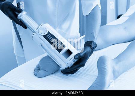 Kosmetologe in Gummihandschuhen bei Endosphären-Therapie an weiblichen Füssen Stockfoto