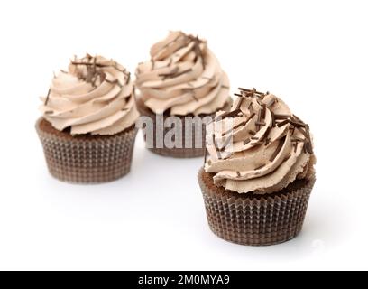 Drei Schokoladen-Cupcakes mit Schlagsahne und Schokoladenstreuseln isoliert auf Weiß Stockfoto