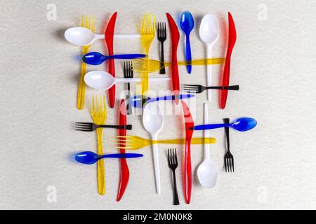 Ansicht von oben farbenfrohe Plastikutensilien auf weißem Hintergrund. Gabeln mit Löffeln und Messern. Stockfoto