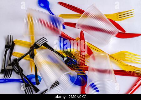 Einweg-Kunststoffbecher mit Gabeln und Löffeln. Konzept der stofflichen Verwertung von Kunststoff und Ökologie. Kunststoffabfälle auf weißer Oberfläche. Stockfoto