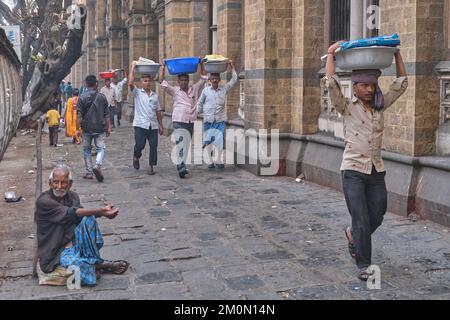 Gepäckträger mit Fischkörben auf dem Kopf, am Chhatrapati Shivaji Maharaj Terminus (CMST) in Mumbai, Indien, um die Körbe mit dem Zug weiterzuleiten Stockfoto