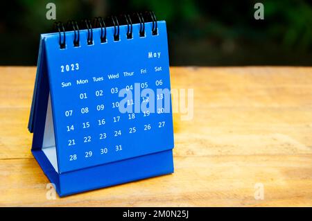 Blauer Tischkalender im Mai 2023 auf Holztisch mit anpassbarem Platz für Text. Stockfoto