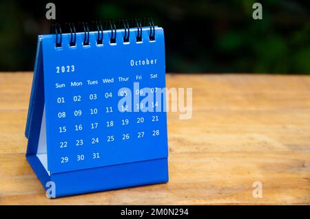 Blauer Tischkalender für Oktober 2023 auf Holztisch mit anpassbarem Platz für Text. Stockfoto