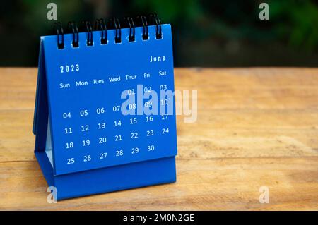 Blauer Tischkalender im Juni 2023 auf Holztisch mit anpassbarem Platz für Text. Stockfoto