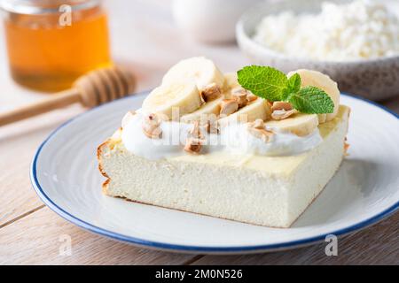 Hüttenkäse-Auflauf, Käsekuchen mit griechischem Joghurt, Banane und Nüssen. Süßer Frühstückskuchen Stockfoto