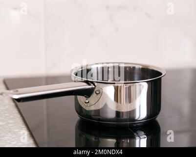 Der Kochtopf aus Edelstahl steht auf dem Induktionskochfeld. Nahaufnahme. Stockfoto