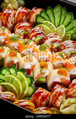 Verschiedene Sushi-Brötchen mit eingelegtem Ingwer, Gurke und Zitrone im Karton Stockfoto