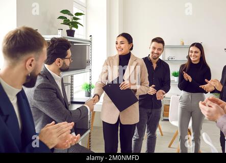 Die freundliche Managerin schüttelt ihrem männlichen Kollegen die Hand und gratuliert ihm zu seiner Arbeit, Gut gemacht. Stockfoto