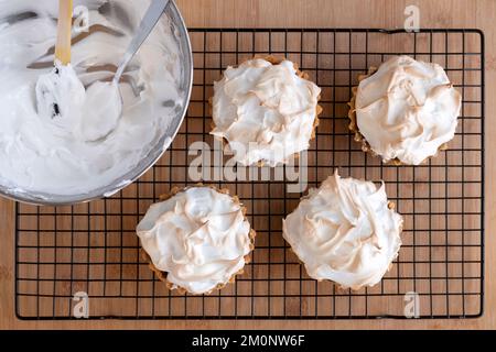 Frisch gebackene Marzipan-Hacktorten oder Kuchen, garniert mit Meringue-Kühlung auf einem Kuchenständer, der gerade aus dem Ofen genommen wurde Stockfoto