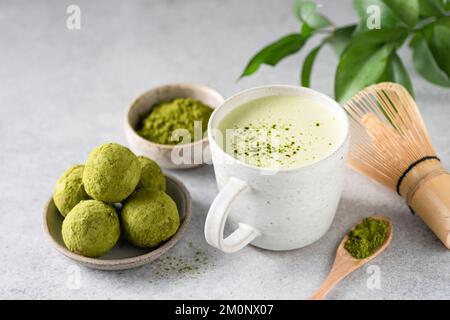 Grüner Tee Matcha Latte im Becher serviert mit veganen Matcha Trüffeln Stockfoto