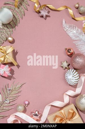 Weihnachtlicher Hintergrund mit glänzenden Zweigen, Dekorationsspielzeug und Geschenkkästen auf pinkfarbenem Hintergrund. Merry Christmas und Happy New Year Concept. Speicherplatz kopieren. Stockfoto