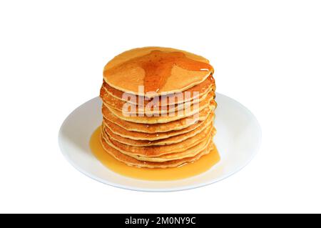 Eine Platte mit leckeren Pfannkuchen, die sich mit Ahornsirup auf weißem Hintergrund stapeln Stockfoto