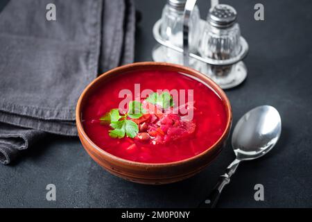 Borschtsch, ukrainische Rote-Beete-Suppe in einer Schüssel auf einem eleganten schwarzen Tisch. Vegetarische rote Suppe Stockfoto