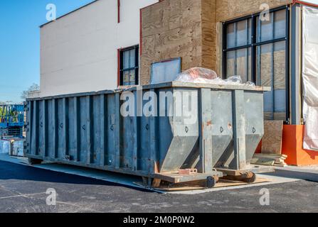 Ein großer, schwerer Müllcontainer neben einem neuen Fast-Food-Restaurant im Bau. Stockfoto