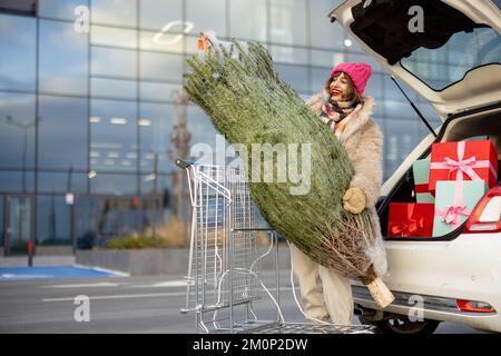 Frau kauft Geschenke und Weihnachtsbaum im Einkaufszentrum Stockfoto