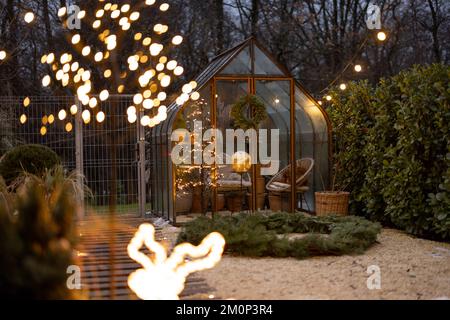 Wunderschöner Hinterhof mit altem Gewächshaus und Weihnachtskranz im Winter Stockfoto