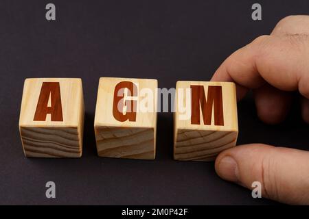 Geschäftskonzept. Auf einer schwarzen Oberfläche stellt ein Mann Würfel mit der Inschrift - AGM Stockfoto