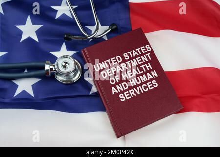 Regelkonzept. Auf der US-Flagge liegt ein Stethoskop und ein Buch mit der Inschrift - United States Department of Health and Human Services Stockfoto