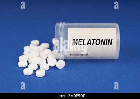 Das Konzept von Pharmakologie und Gesundheit. Auf einer blauen Oberfläche sind Pillen und ein staubiges Gefäß mit der Aufschrift - Melatonin Stockfoto