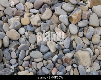 Steinhintergrund von runden Kopfsteinpflastersteinen in verschiedenen Grautönen und Brauntönen, natürliche Textur von abgerundeten Fluss- oder Meeressteinen Vollrahmen, Steine und mi Stockfoto