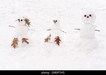 Süße drei weiße Schneemänner stehen vor dem schneebedeckten Hintergrund Stockfoto