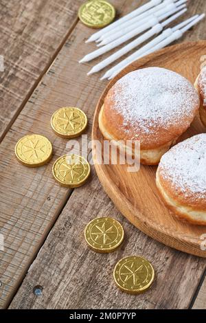 Frohes Chanukka. Süße Hanukka-Donuts, Geschenkschachteln, weiße Kerzen und Schokoladenmünzen auf altem Holzhintergrund. Bild und Konzept des jüdischen Urlaubs Stockfoto