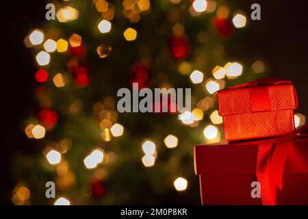 Goiânia, Goias, Brasilien – 07. Dezember 2022: Zwei Geschenkschachteln, rot, mit Schleife und einem Weihnachtsbaum im Hintergrund. Stockfoto