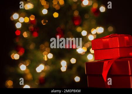 Goiânia, Goias, Brasilien – 07. Dezember 2022: Zwei Geschenkschachteln, rot, mit Schleife und einem Weihnachtsbaum im Hintergrund. Stockfoto