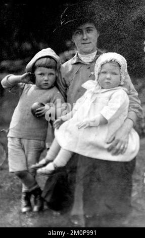 1915 posierte Sarah Gregory im Alter von 39 Jahren und hielt ihre Tochter Ida Gregory im Alter von 1, während ihr Sohn Alfred Gregory im Alter von 2 Jahren neben ihnen steht. Sarah Gregory leitete mit ihrem Mann Charles Gregory, der das Foto machte, einen Lebensmittelladen in Blackburn, Lancashire, Großbritannien. Alfred Gregory wurde später Bergsteiger und verantwortlich für die Fotografie auf der britischen Mount Everest Expedition von 1953, die den ersten Aufstieg auf den Mount Everest machte. Ida Gregory gründete mit ihrem Bruder und ihrem Mann nach dem 2. Weltkrieg ein Reisebüro. Charles Gregory starb 1918 als Soldat im 1. Weltkrieg. Stockfoto